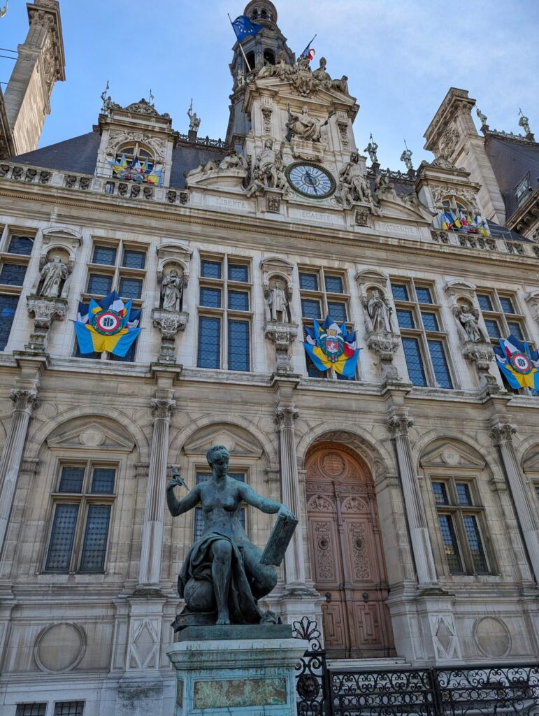 Detailansicht des Hôtel de Ville in Paris mit einer Statue und reich verzierten Fassadenelementen.